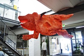 rote risige Hundeskulptur, in einer Eingangshalle hängend