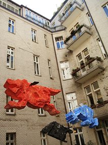 drei große farbige Skulpturen, im Innenhof eines Wohnblocks hängend