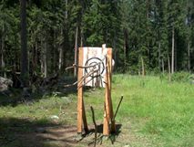 Skulptur aus roh behauenem Holz, Zielscheibe, eingesteckte Äste, halbes Schwein