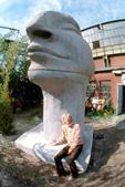 Die Künstlerin an der 2-Personen-hohen Skulptur sitzend
